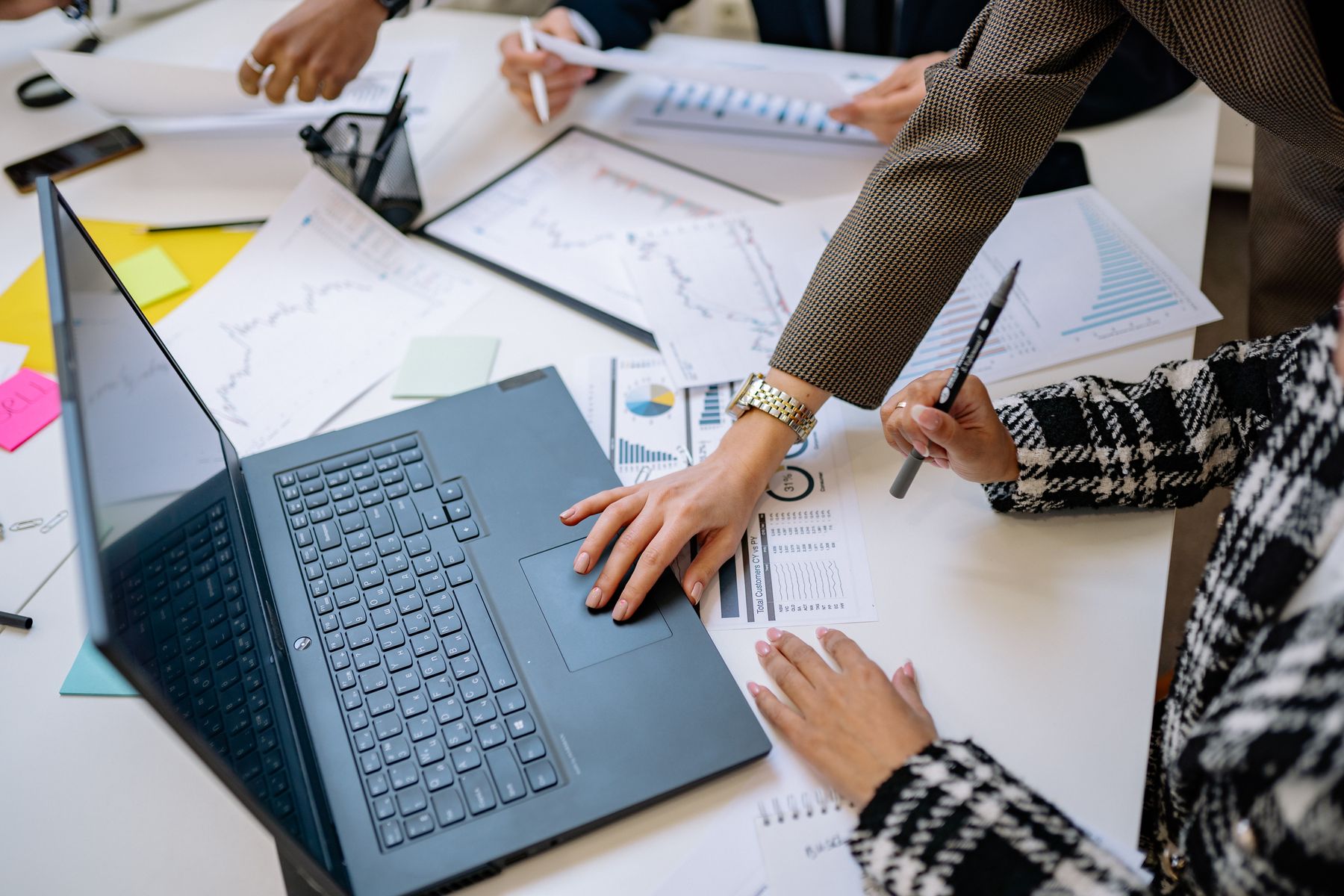 Business team reviewing financial charts, reports, and data around a laptop