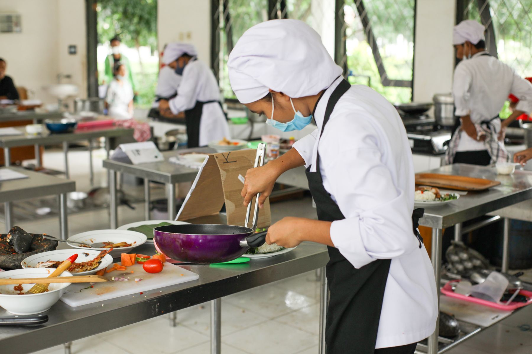 Culinary students practising food preparation in a professional teaching kitchen