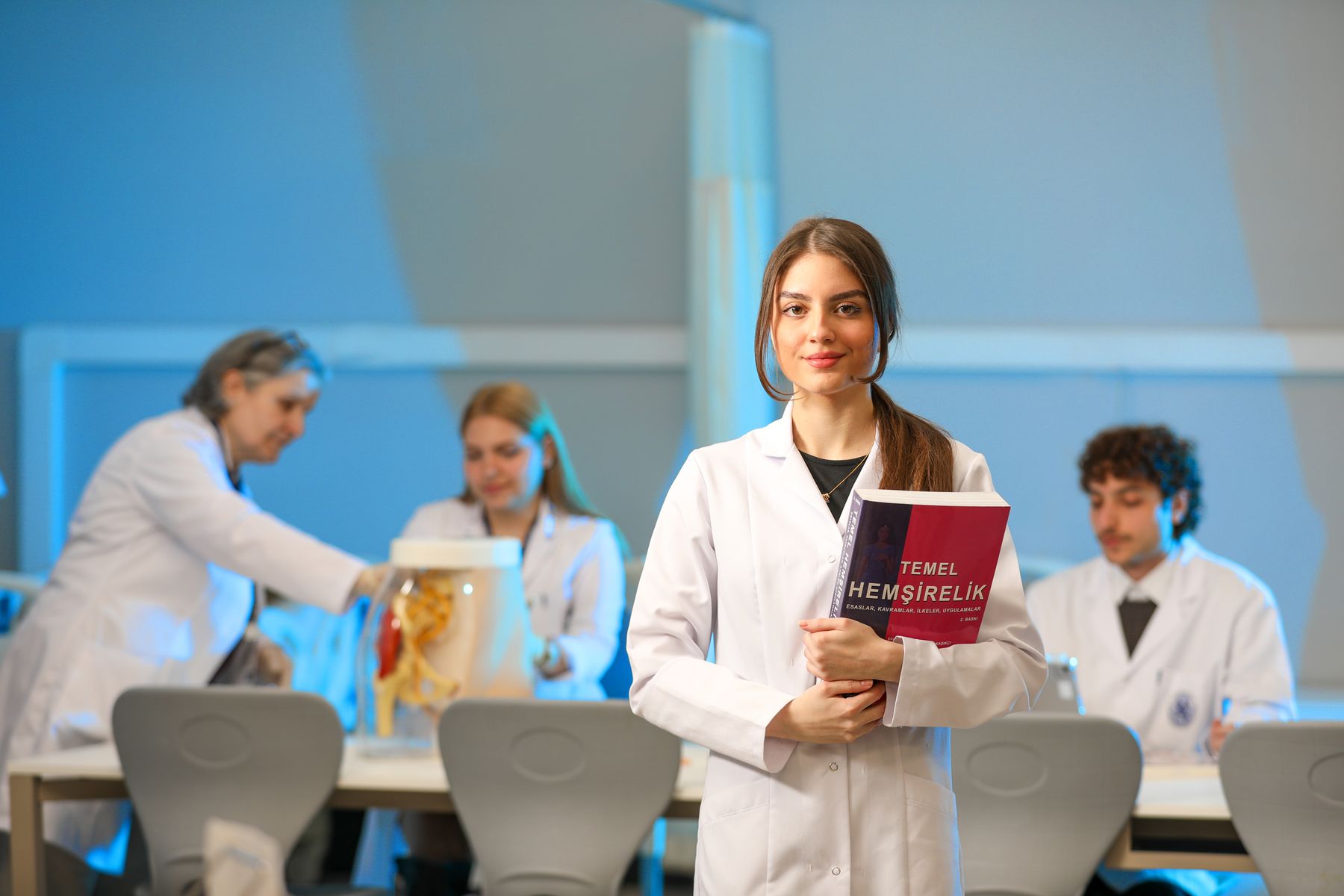 Nursing students studying with an anatomy model and nursing textbook in a university laboratory