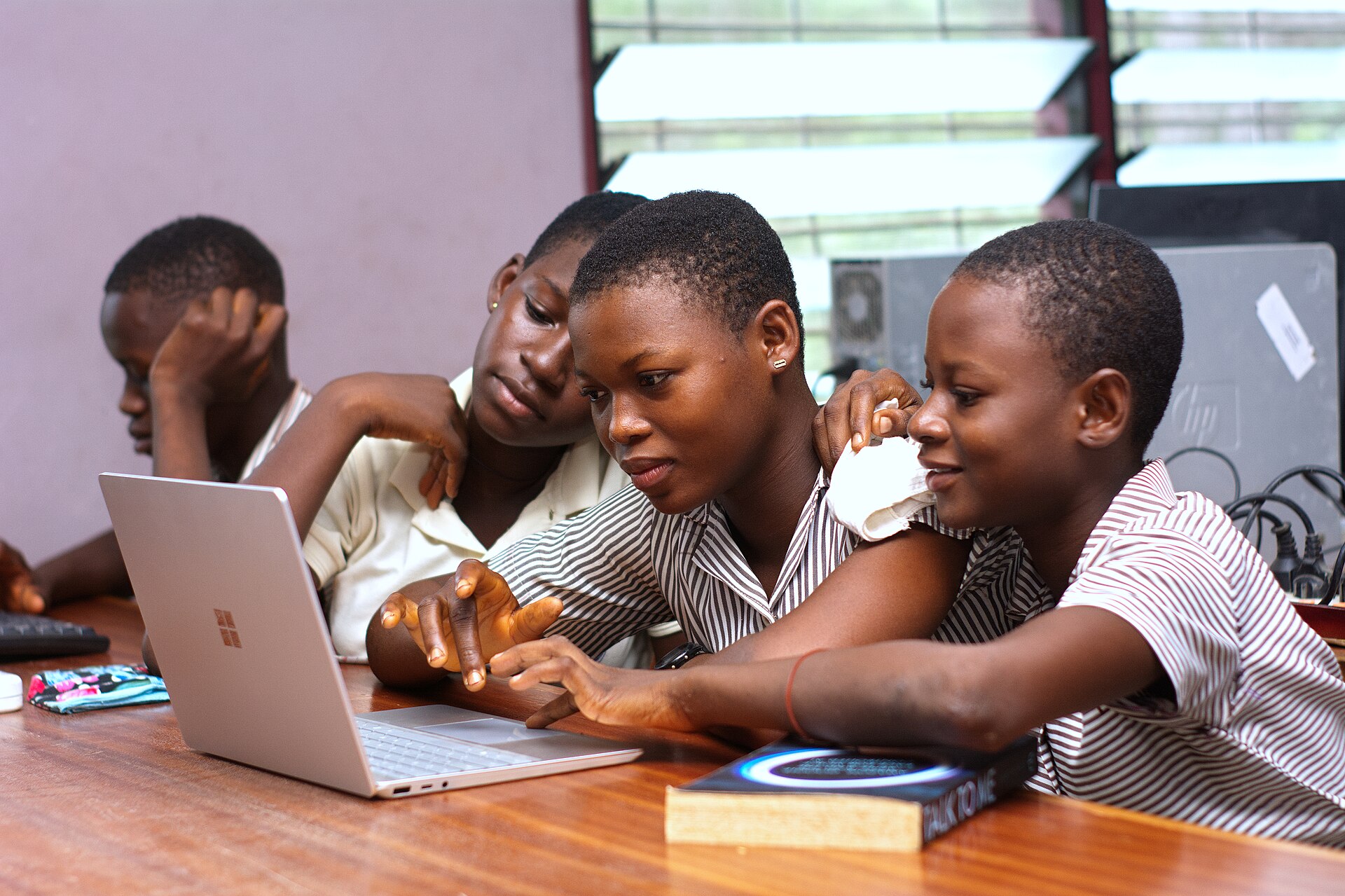 Students collaborating around a laptop during an academic study session